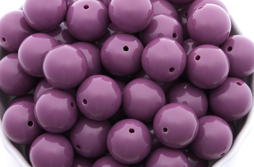 purple beads in a white bowl on a white background