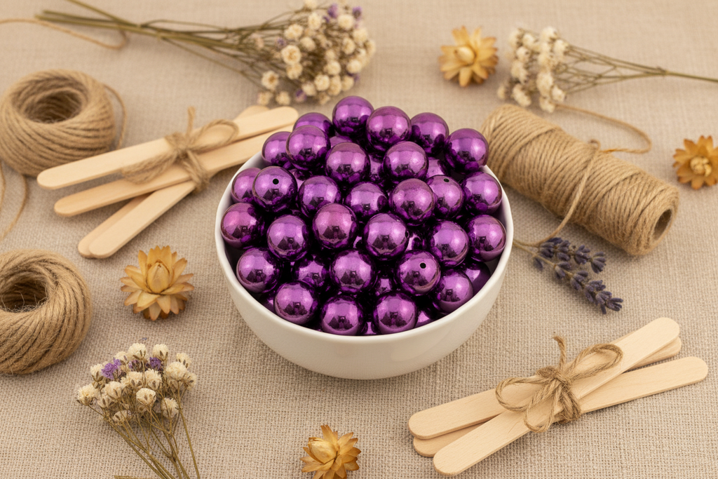 White bowl filled with metallic purple beads on a textured surface with twine and flowers.