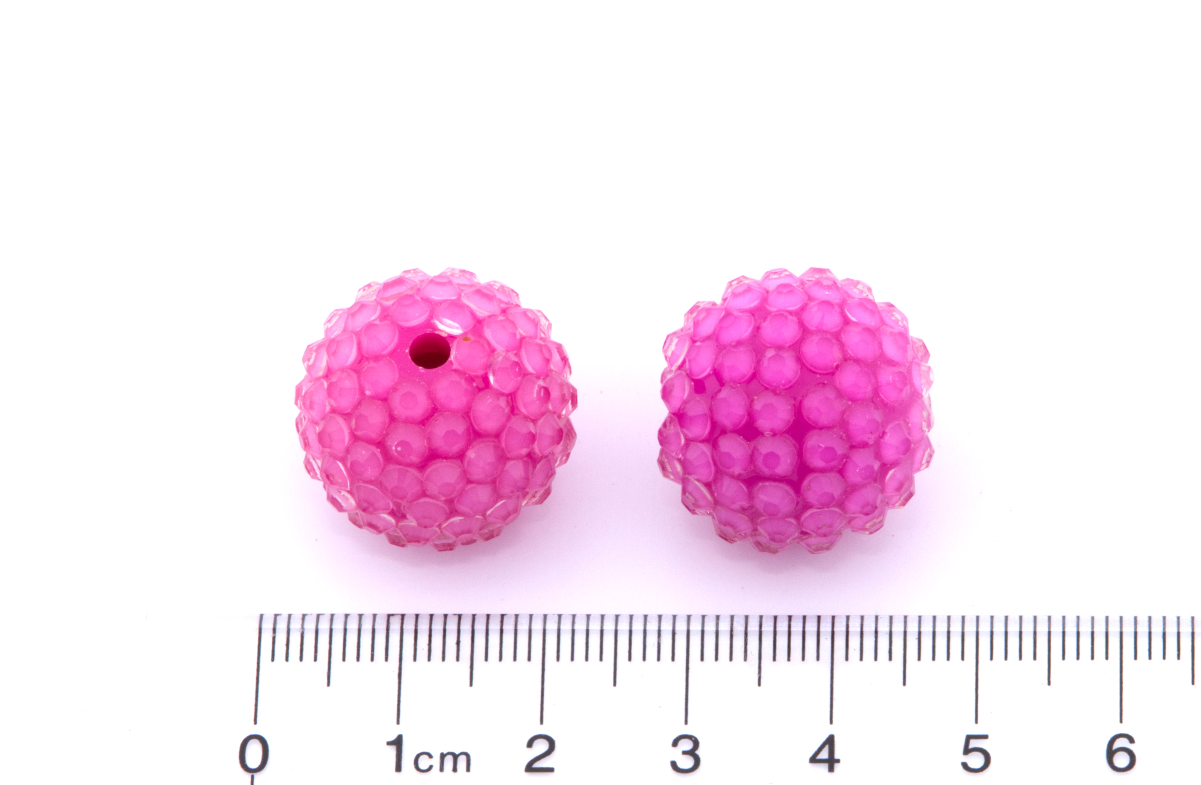 Two pink rhinestone bubblegum beads shown next to a cm ruler for scale on a white background.