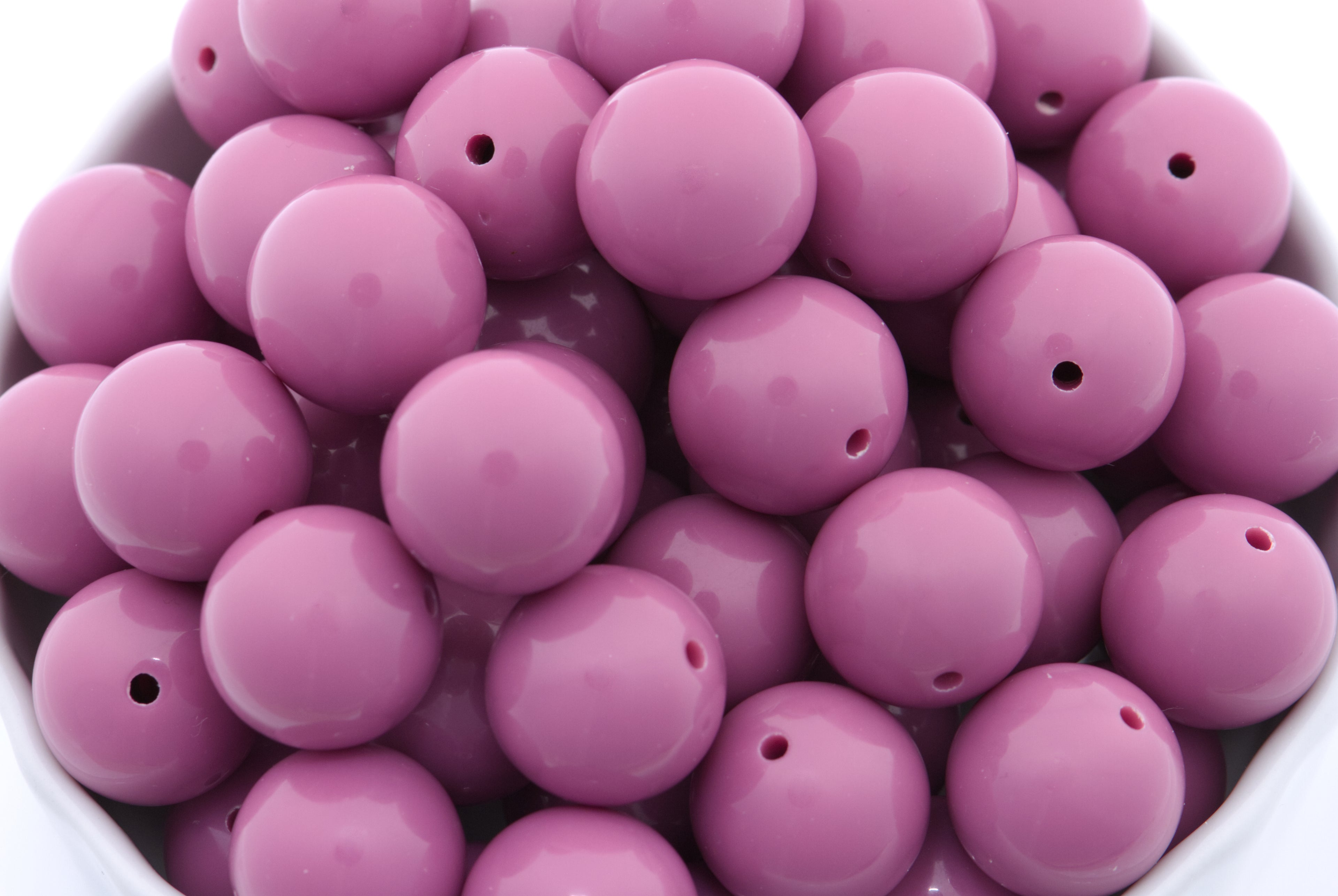 purple beads in a white bowl on a white background
