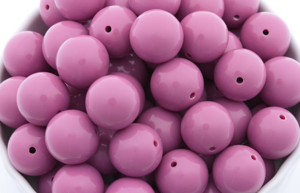 purple beads in a white bowl on a white background 