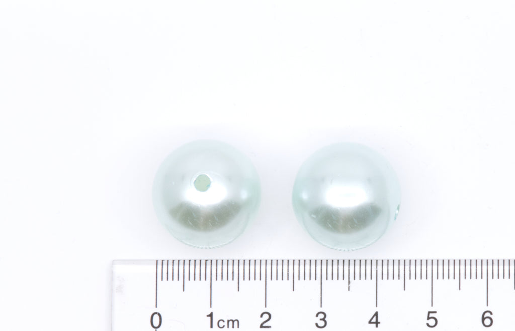 two blue bubblegum beads next to a ruler for scale on a white background