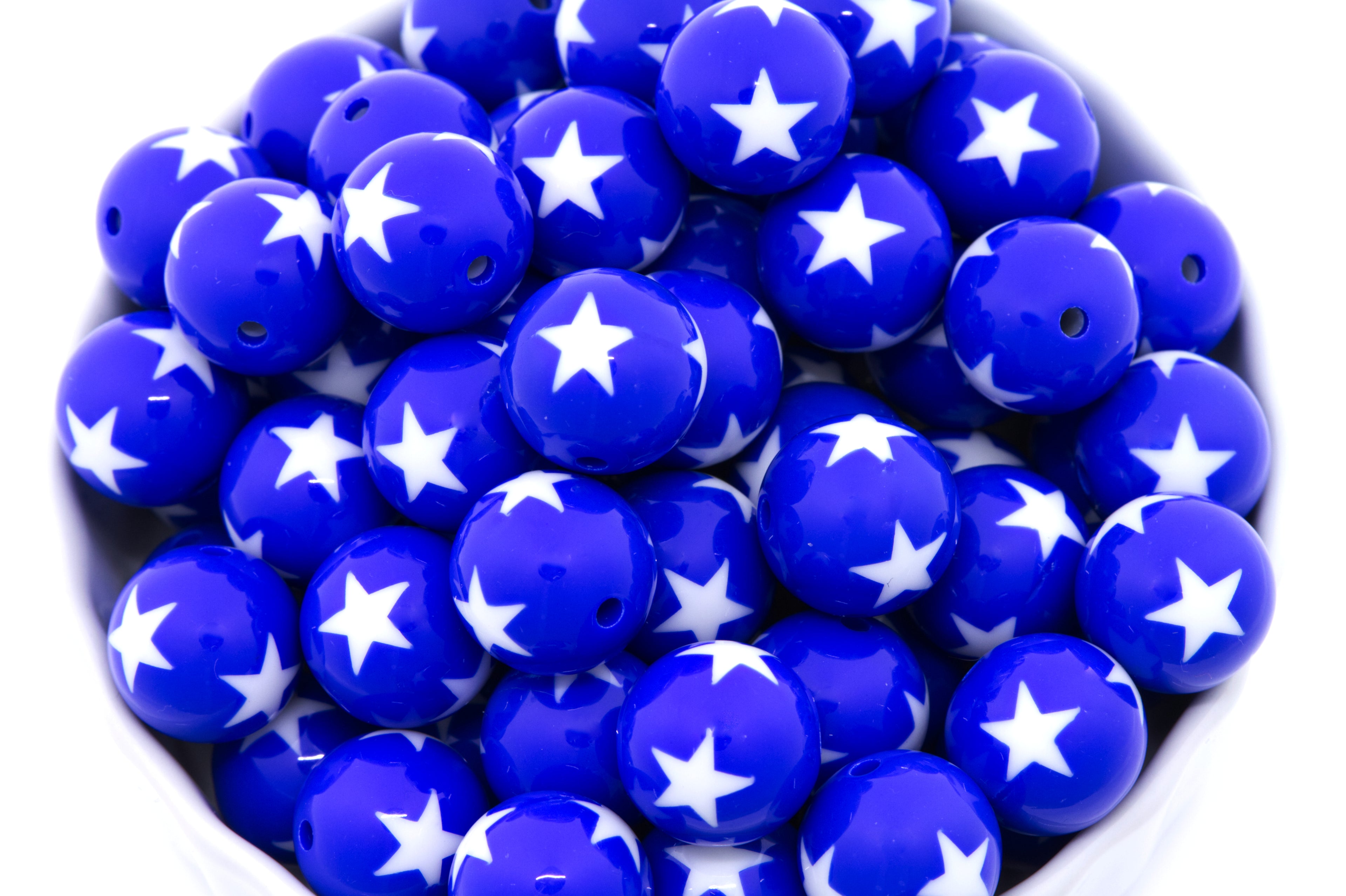 Blue beads with white star patterns in a white bowl