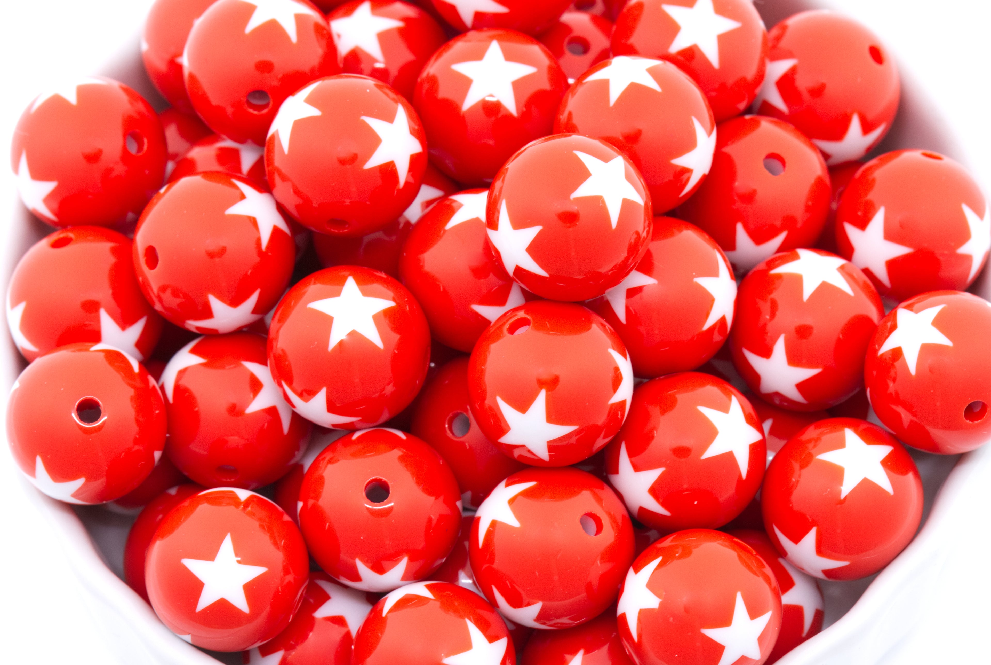 Red beads with white star patterns in a white container