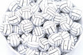 A pile of volleyball bubblegum beads, arranged in a white bowl against a white background.