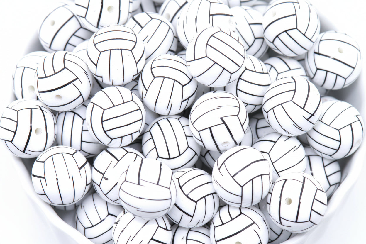 A pile of volleyball bubblegum beads, arranged in a white bowl against a white background.