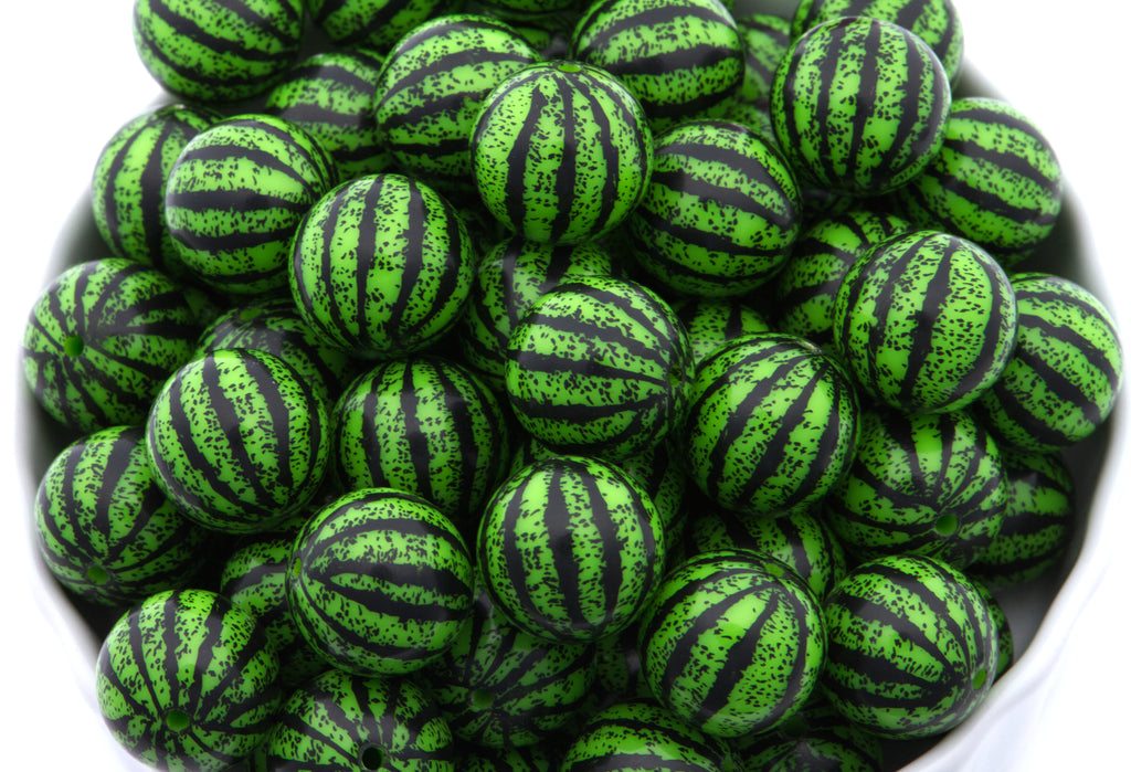 A pile of watermelon striped bubblegum beads displayed in a white bowl against a white background.