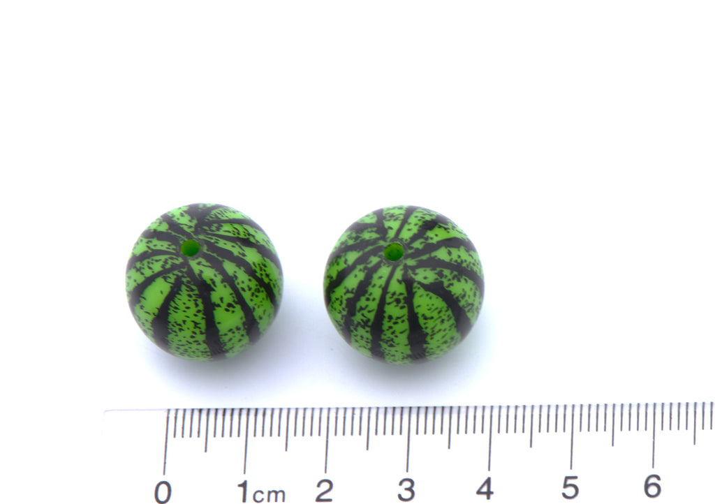 Two round green and black watermelon-themed beads shown next to a cm ruler for scale on a white background.