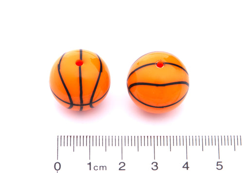 Two orange basketball beads cm ruler for scale on a white background.