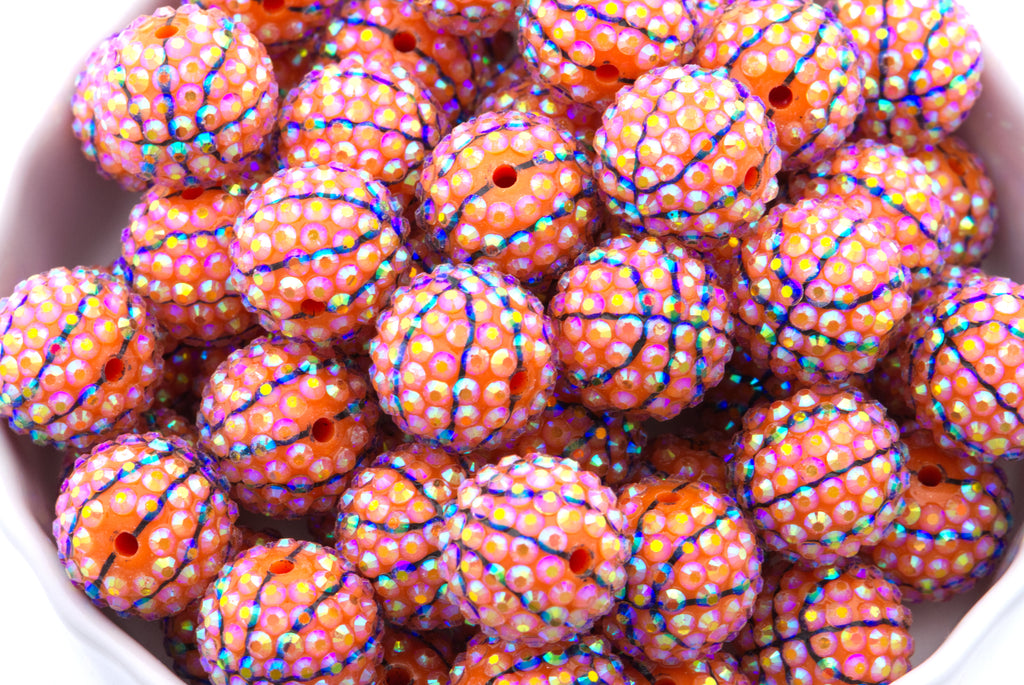 Colorful basketball rhinestone beads in a white bowl on a white background 