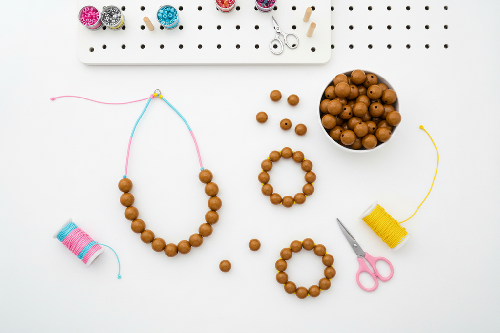 Beaded jewelry-making items on a white surface with tools and materials.
