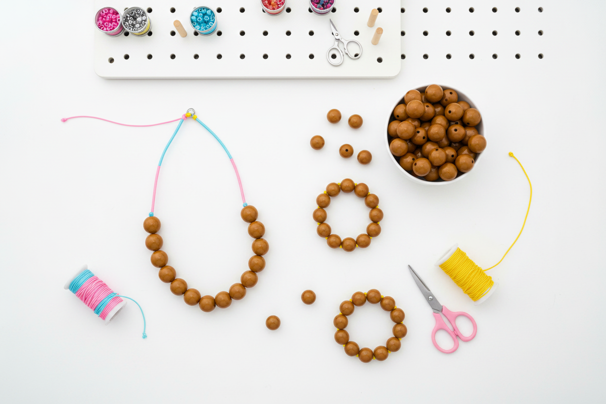 Beaded jewelry-making items on a white surface with tools and materials.
