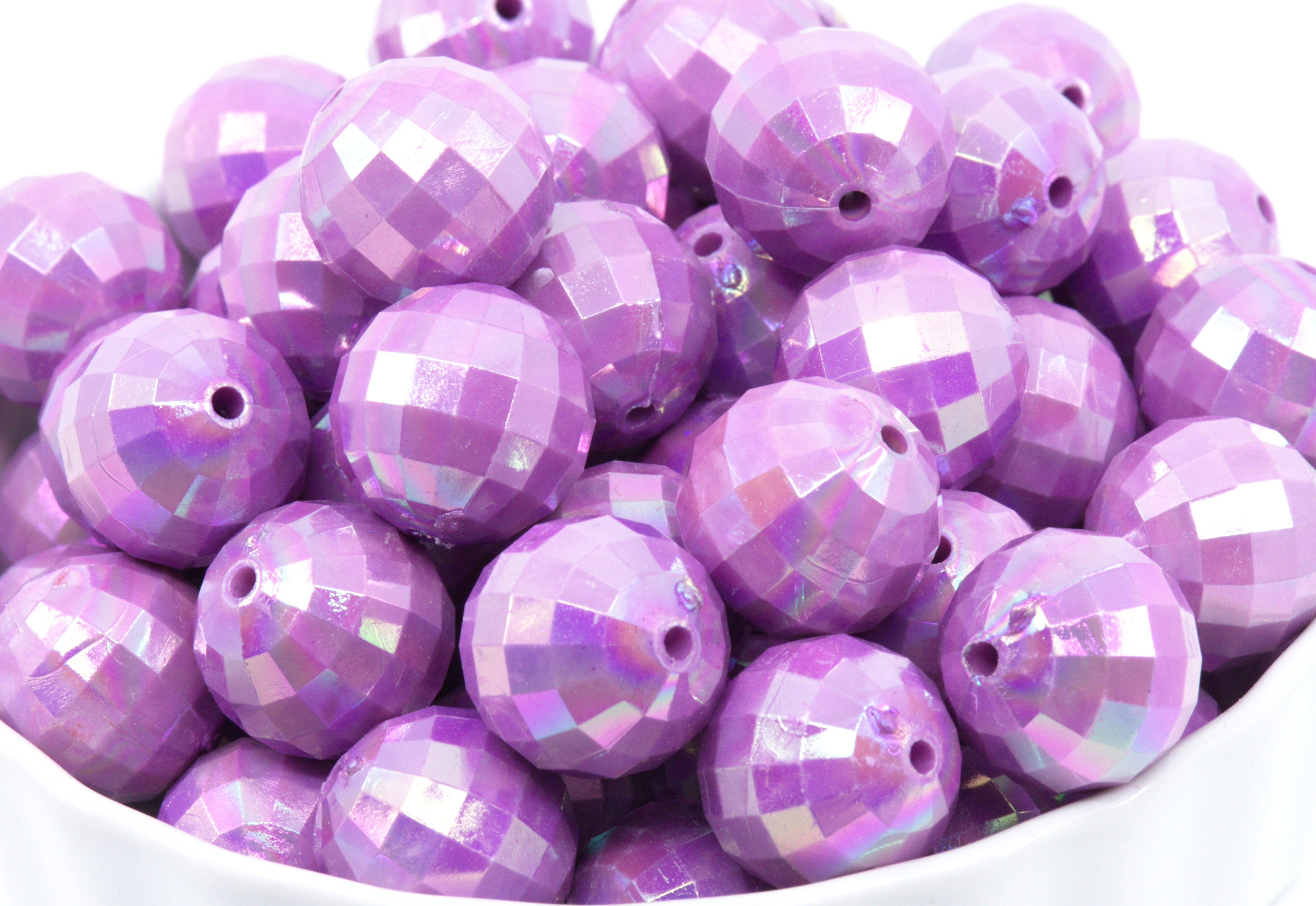 Purple faceted beads in a white bowl on a white background