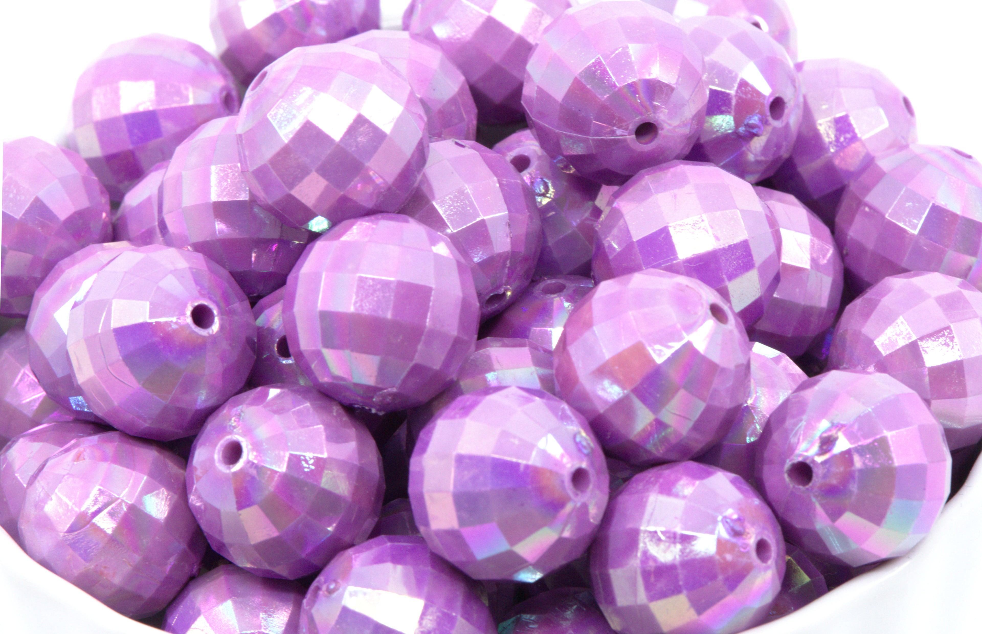 Purple faceted beads in a white bowl on a white background
