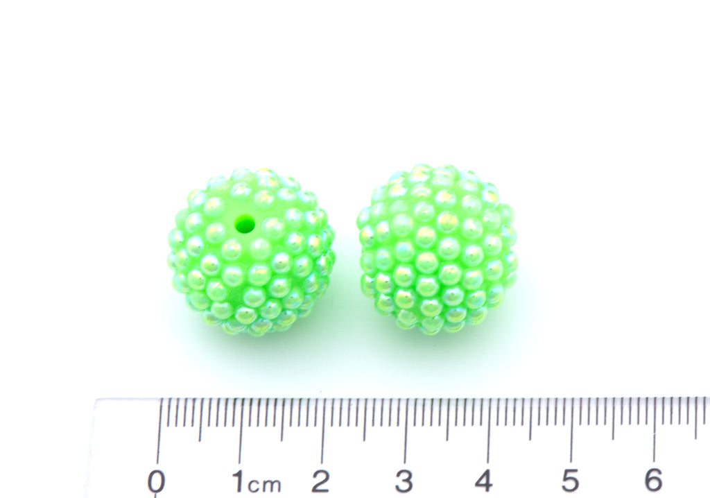 Two bright green beaded round beads shown on a white background with a cm ruler at the bottom for scale.