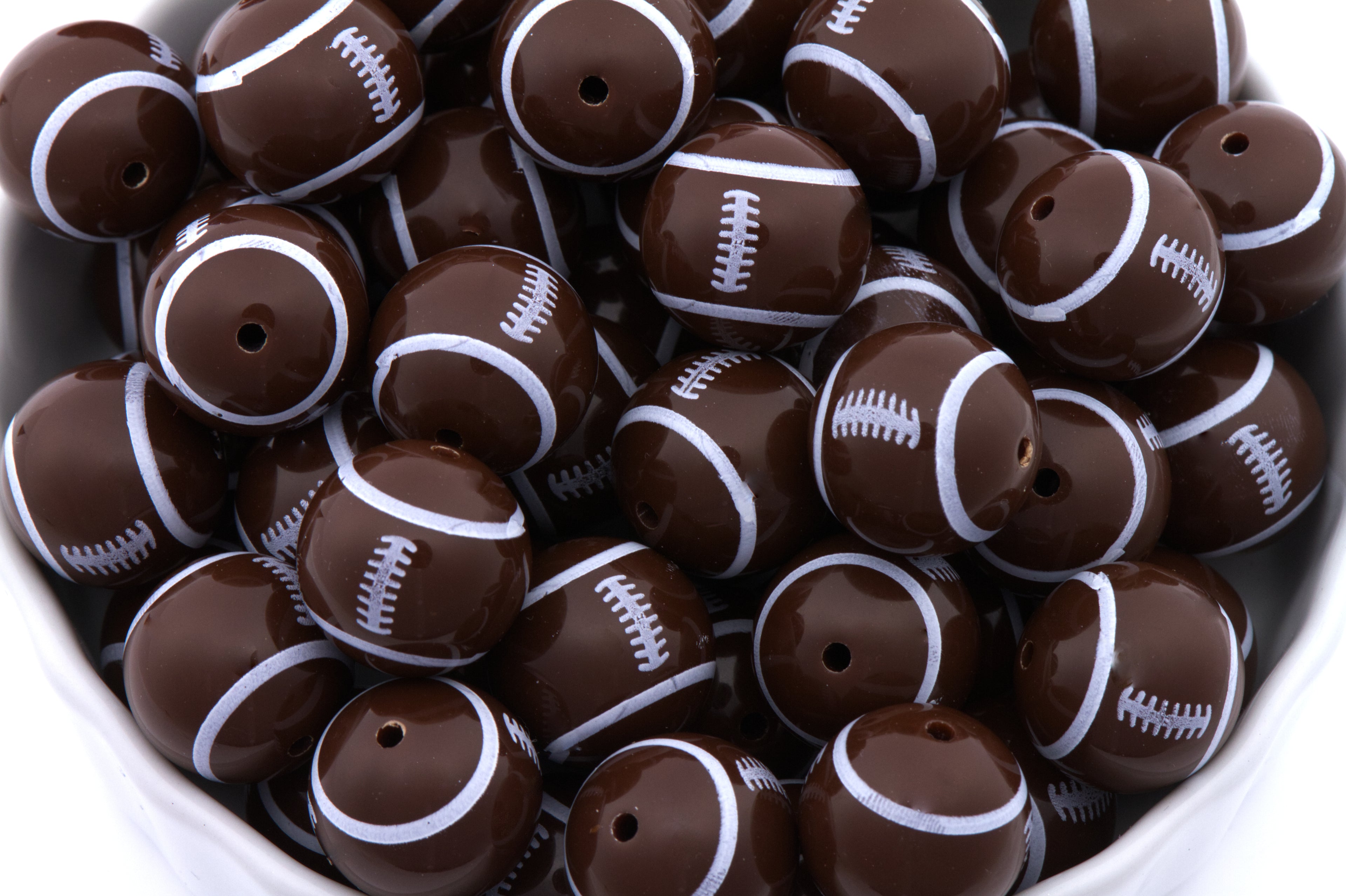 Brown and white football-shaped beads in a bowl