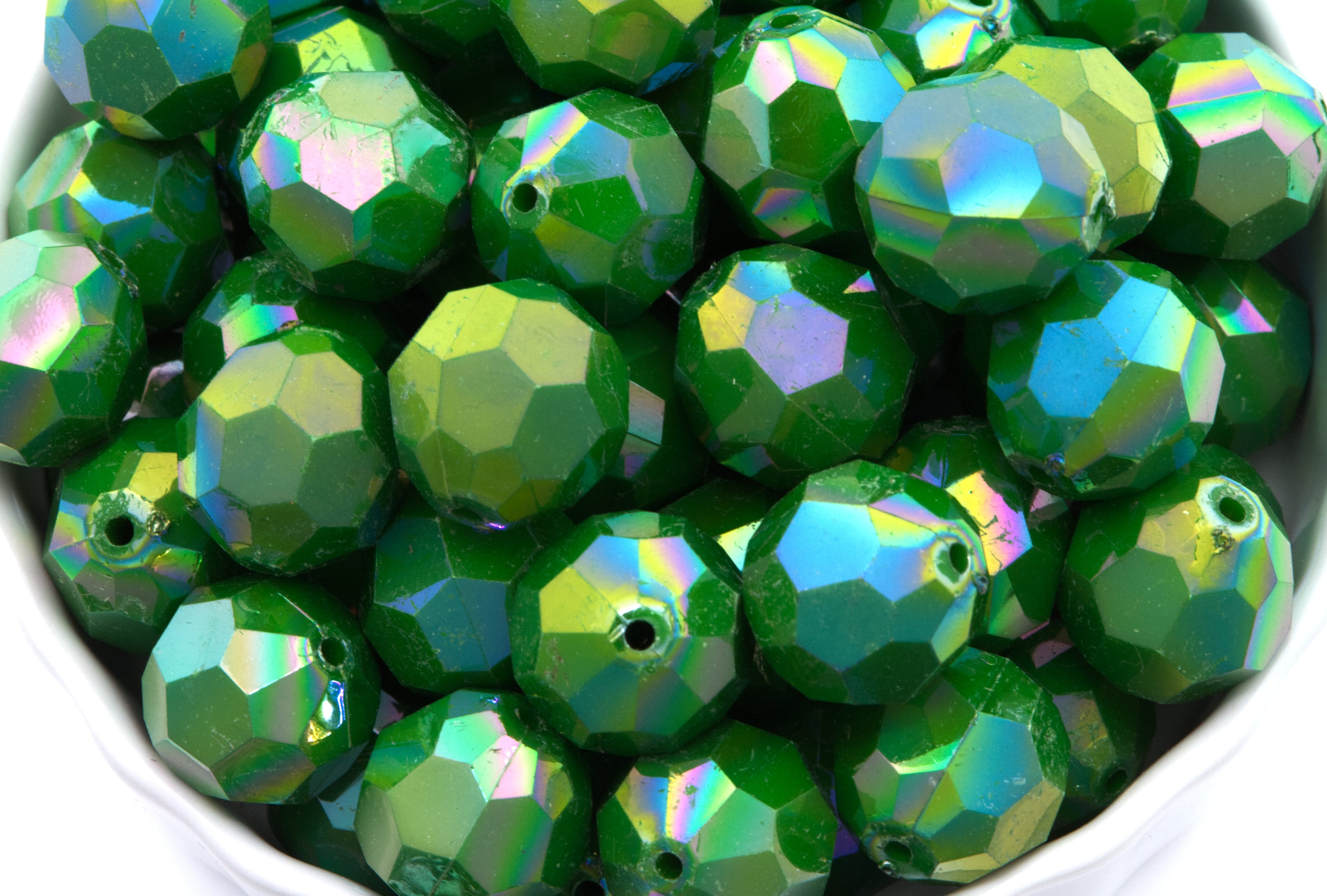 Green faceted beads in a white bowl on a white background