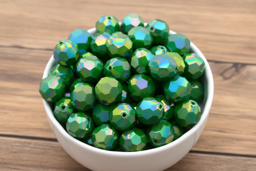 Green faceted beads in a white bowl on a wooden surface
