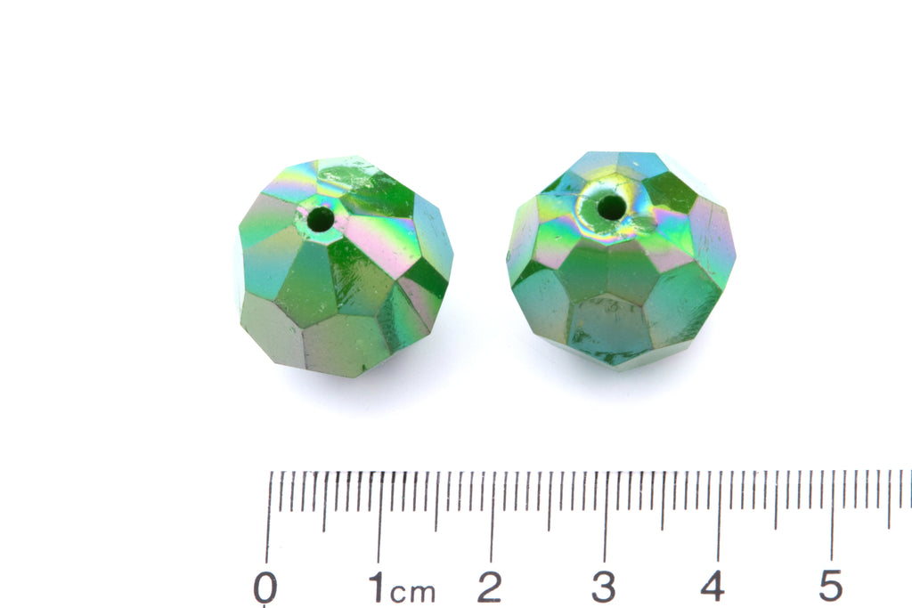 Two faceted green beads with a ruler for scale on a white background
