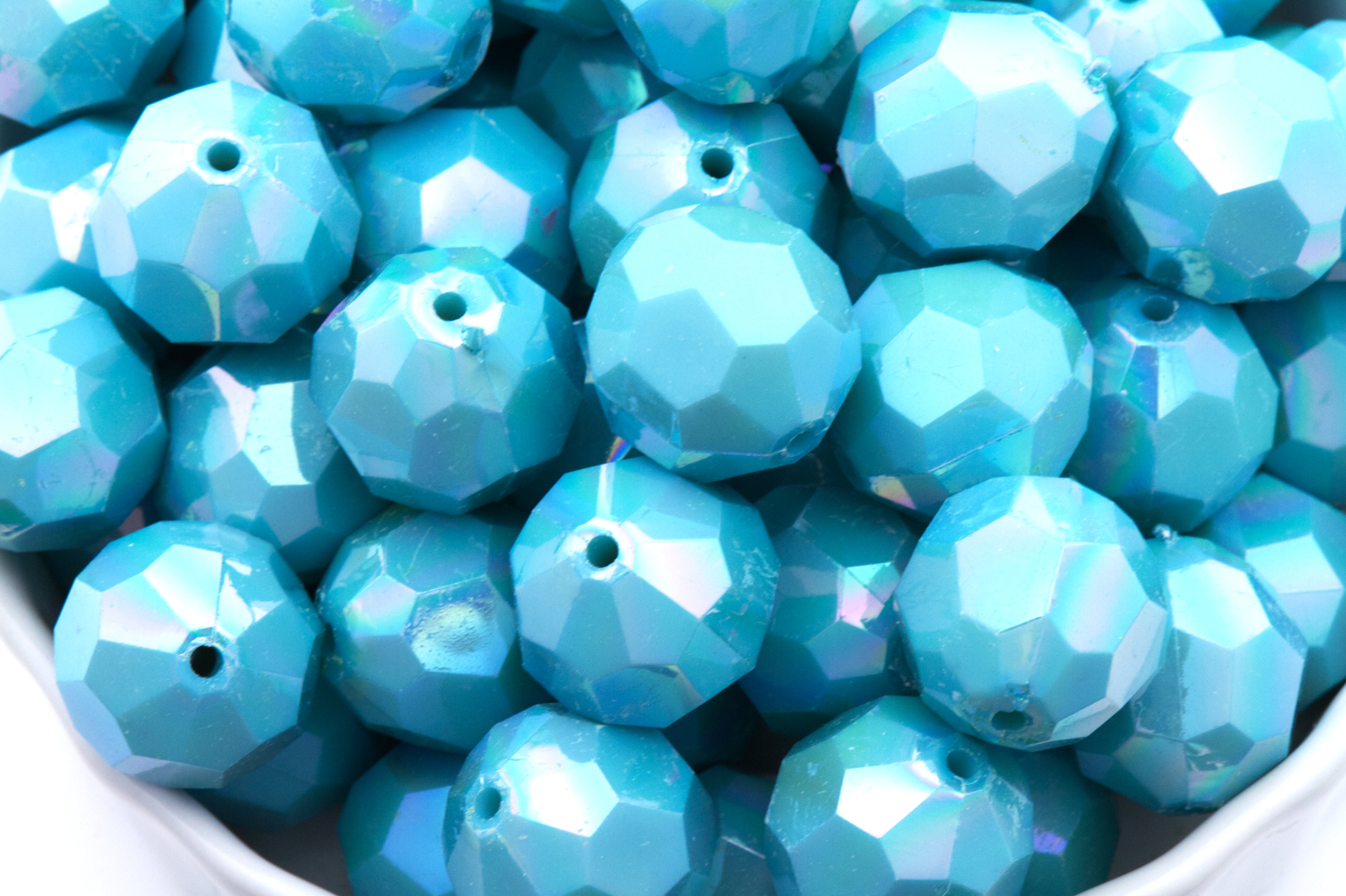 blue faceted beads in a white bowl on a white background