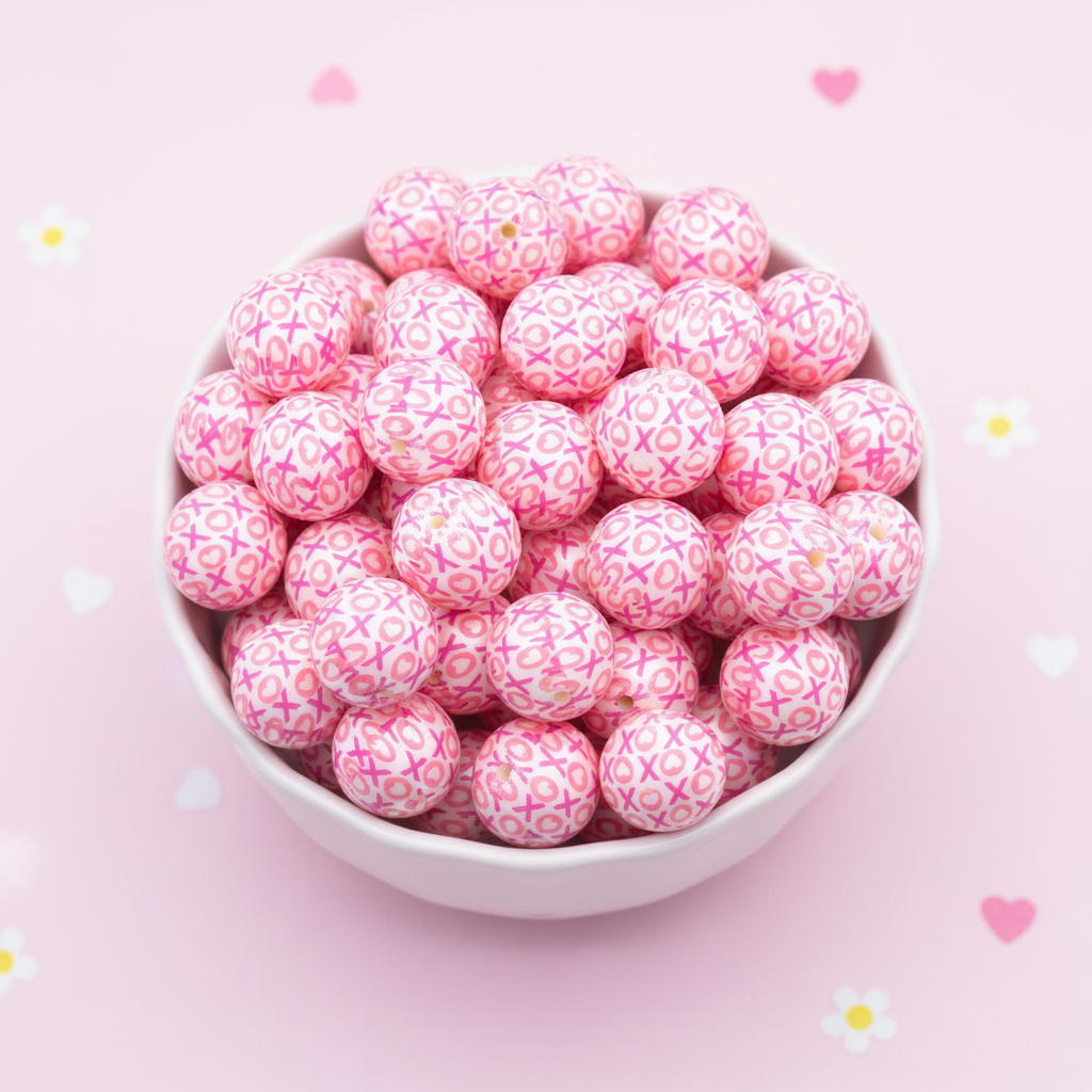 Pink beads with XOXO pattern in a white bowl on a pink background