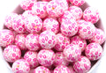 Pink bubblegum beads with kiss print pattern in a white bowl