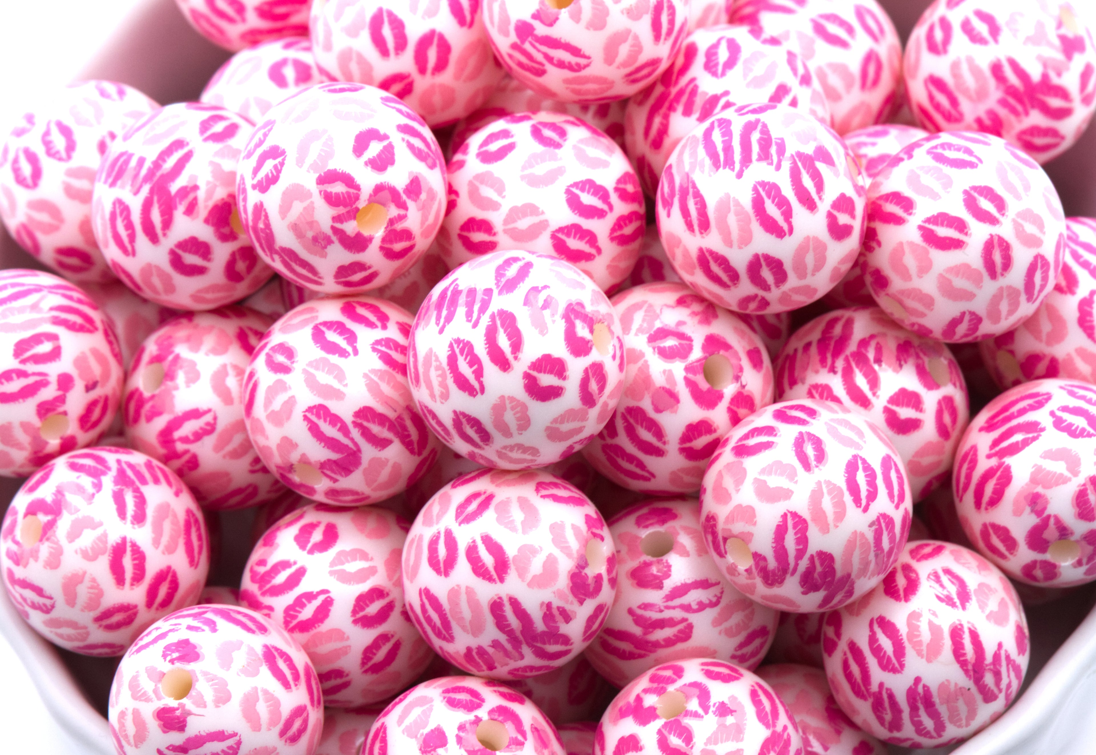 Pink bubblegum beads with kiss print pattern in a white bowl