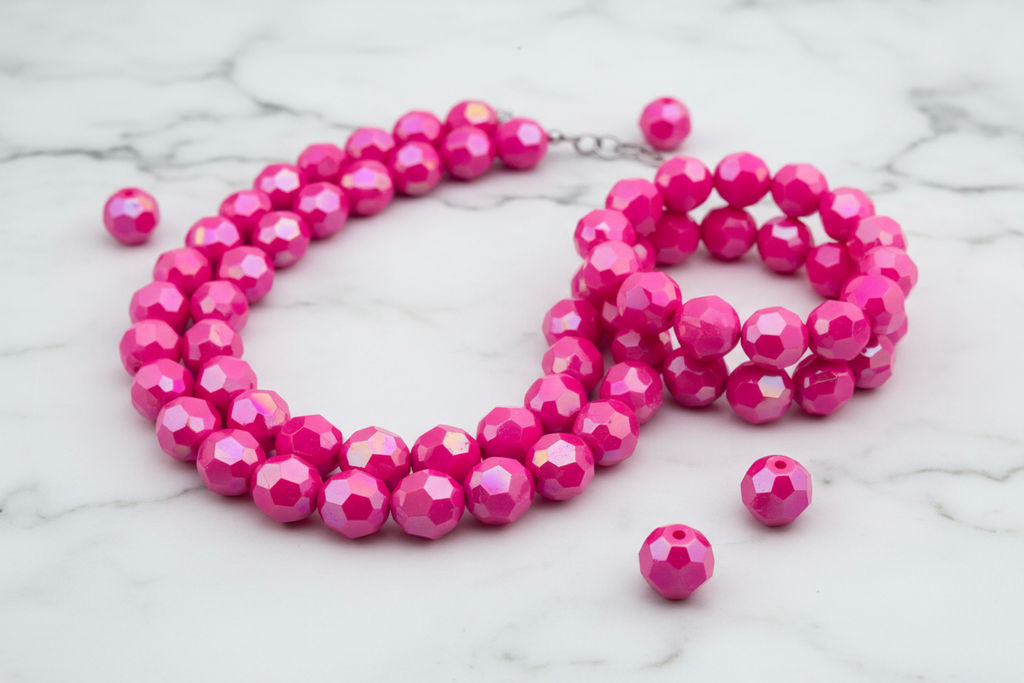 Pink faceted beads displayed as a beaded necklace and bracelet on a marble surface