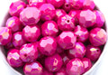 pink faceted beads in a white bowl on a white background