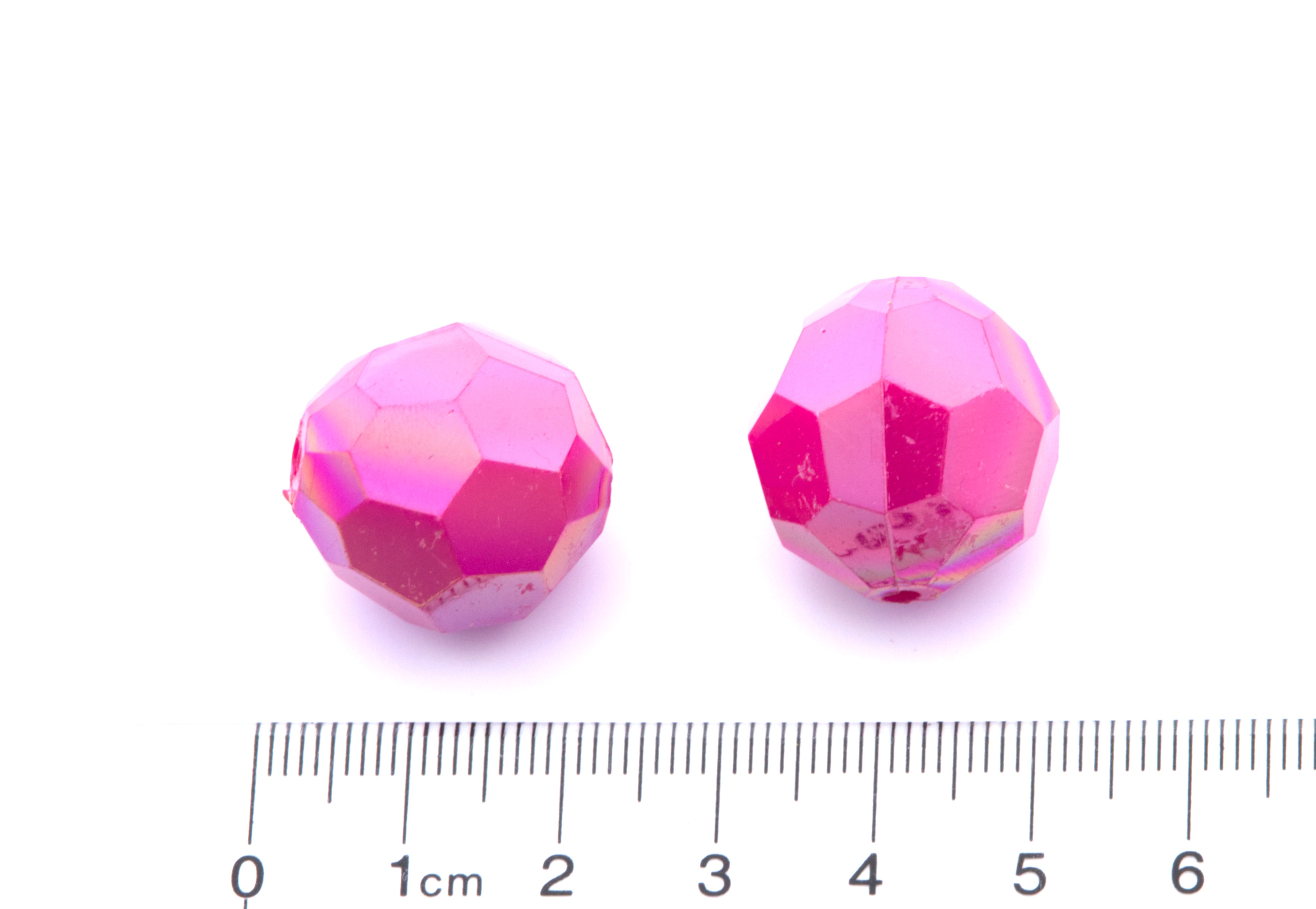 Two pink faceted beads with a ruler for scale on a white background