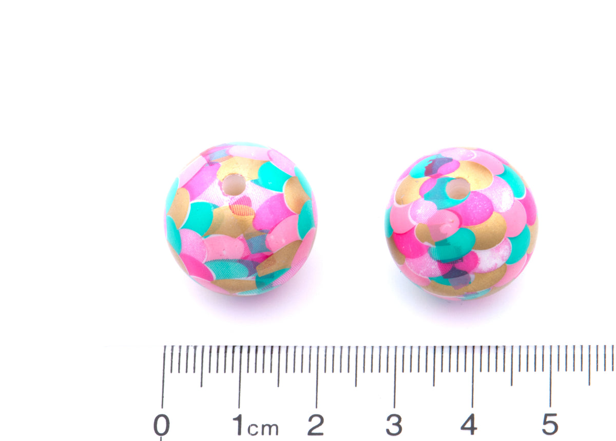 Two round 20mm bubblegum beads in a mermaid scale pattern of pink, teal, and gold, shown next to a cm ruler for scale on a white background.
