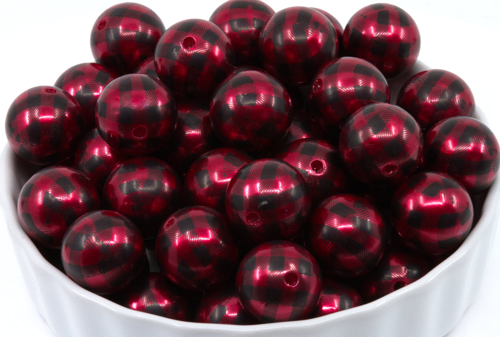 A white bowl filled with red and black buffalo plaid round beads on a white background.