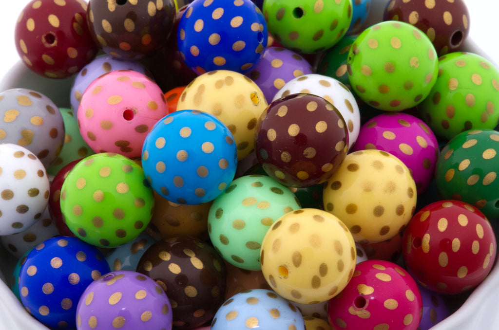 A close-up of colorful round beads with small gold polka dots, arranged in a white container. The beads come in many colors including blue, green, pink, yellow, purple, brown, red, and white.