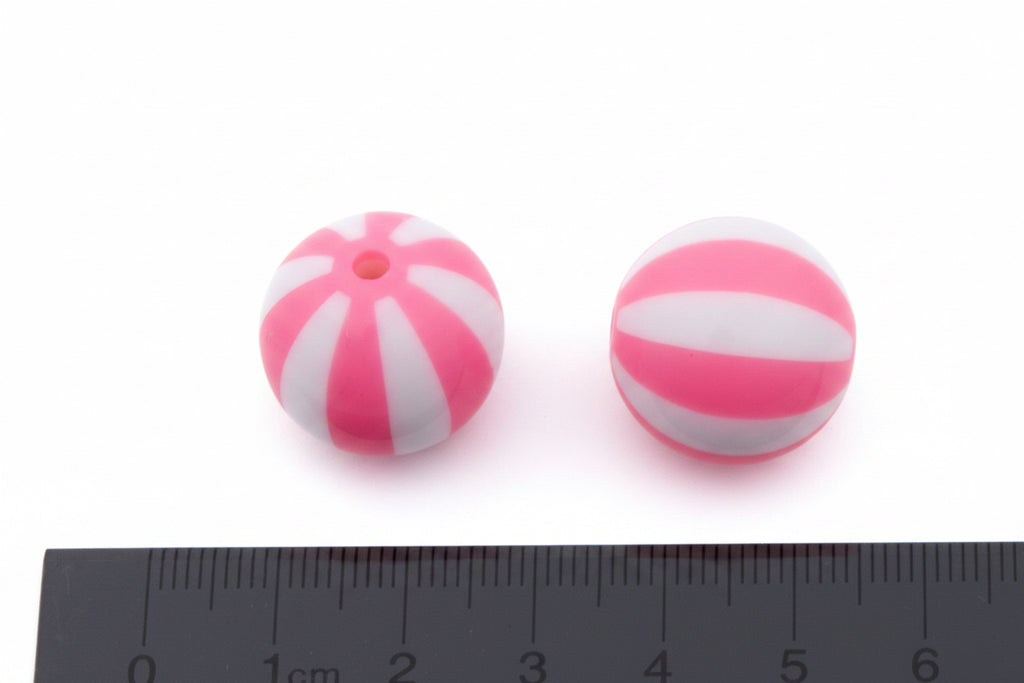 Two round pink and white striped beads shown on a white background with a ruler at the bottom for scale.
