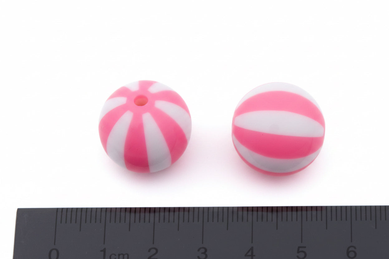 Two round pink and white striped beads shown on a white background with a ruler at the bottom for scale.