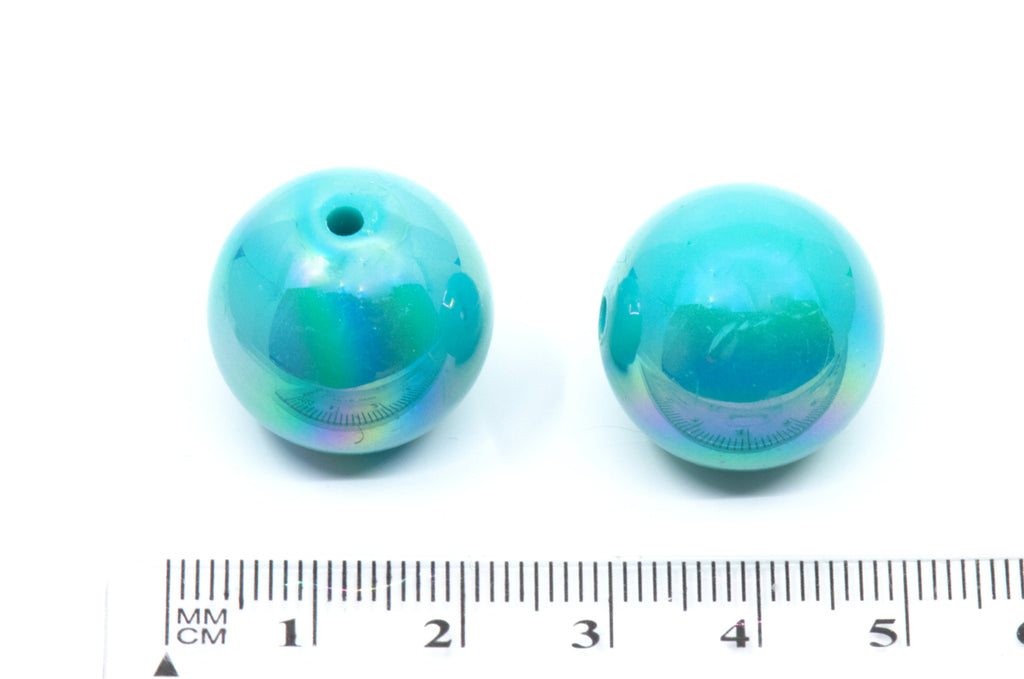 blue iridescent beads with a ruler for scale on a white background