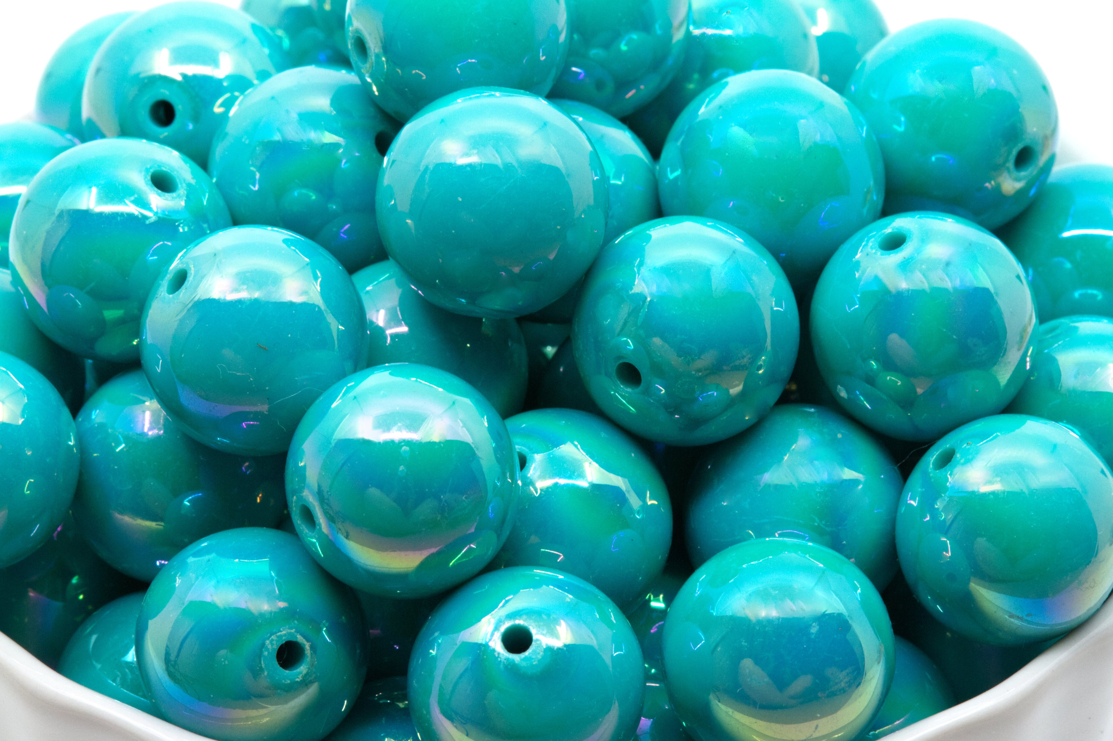 blue iridescent beads in a white bowl on a white background