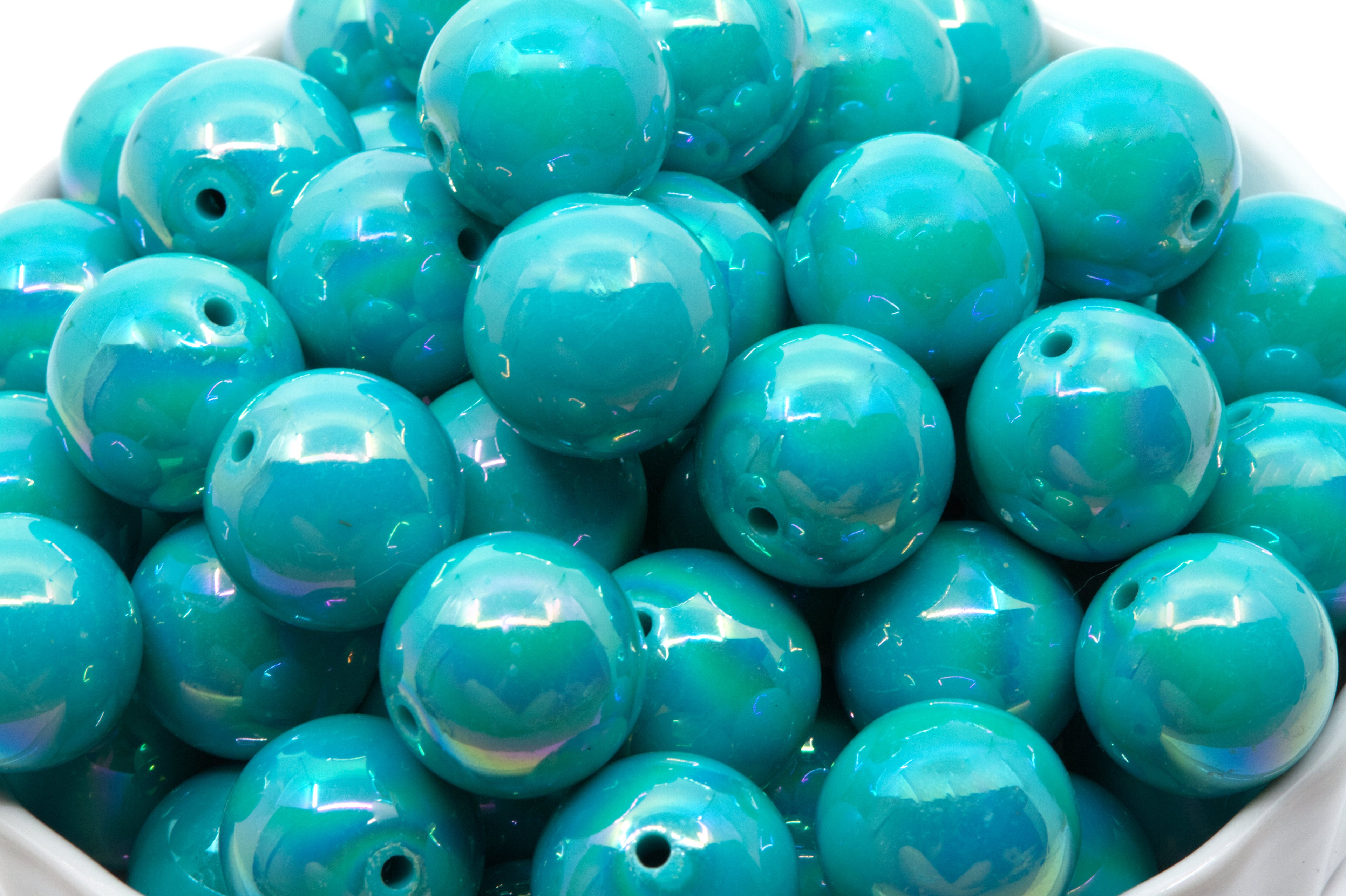 blue iridescent beads in a white bowl on a white background 
