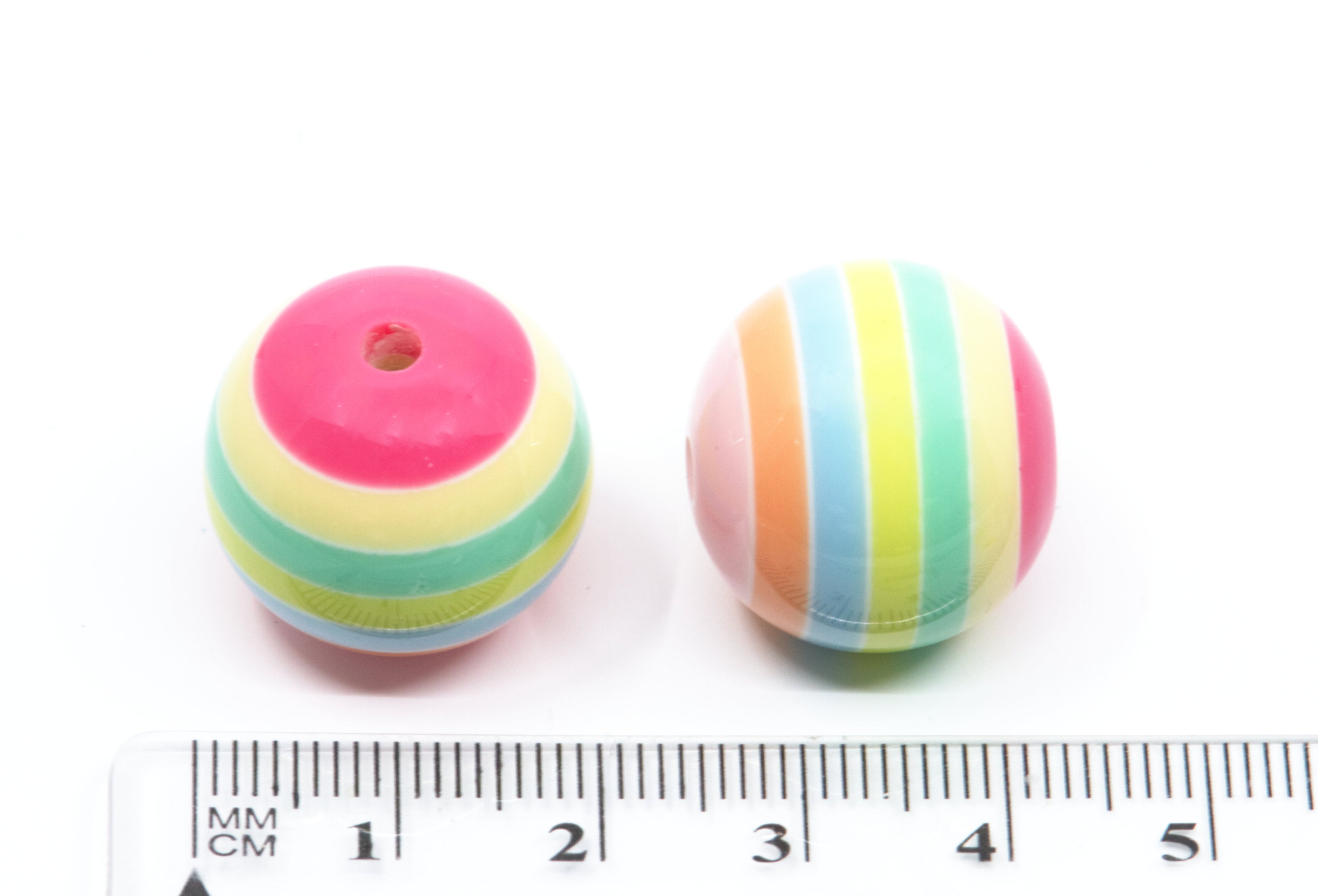 Two pastel striped beads with pastel rainbow stripes, shown next to a cm ruler for scale on a white background.