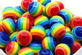 A pile of rainbow striped bubblegum beads, shown close-up in a white container against a white background.