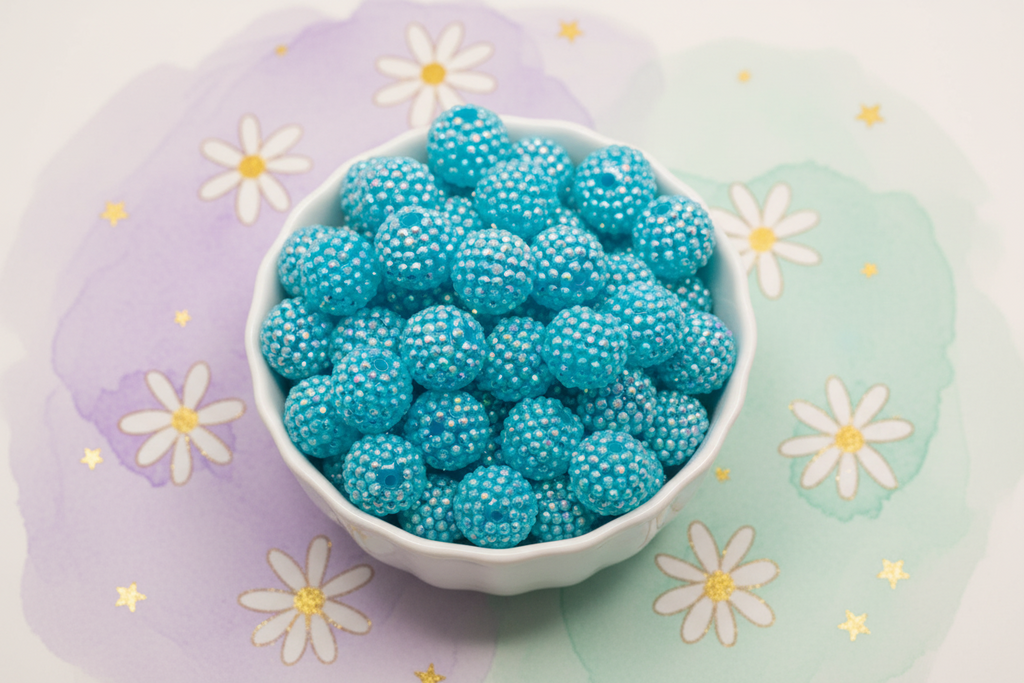 blue rhinestone beads in a white bowl on a floral background 