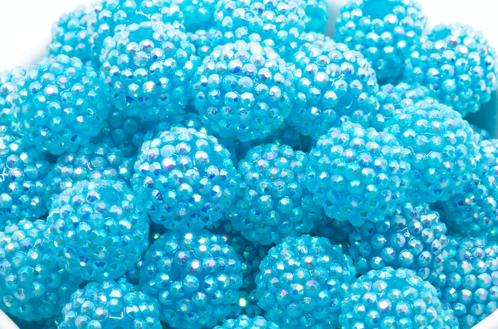 close up photo of blue rhinestone beads in a white bowl 