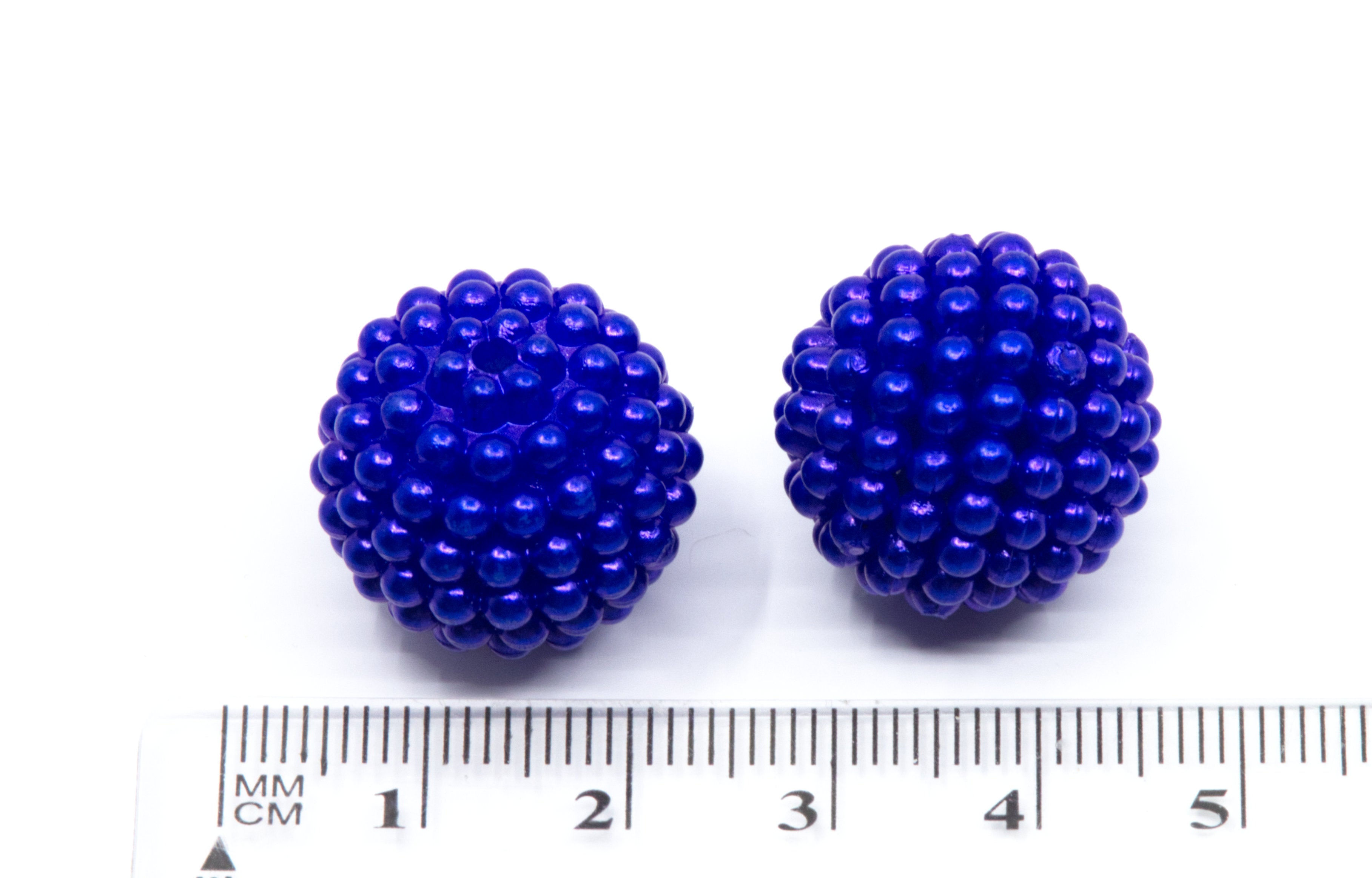 Two blue beaded bubblegum beads shown on a white background with a centimeter ruler underneath for scale.