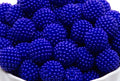A close-up of blue beaded bubblegum beads piled in a white bowl against a white background.