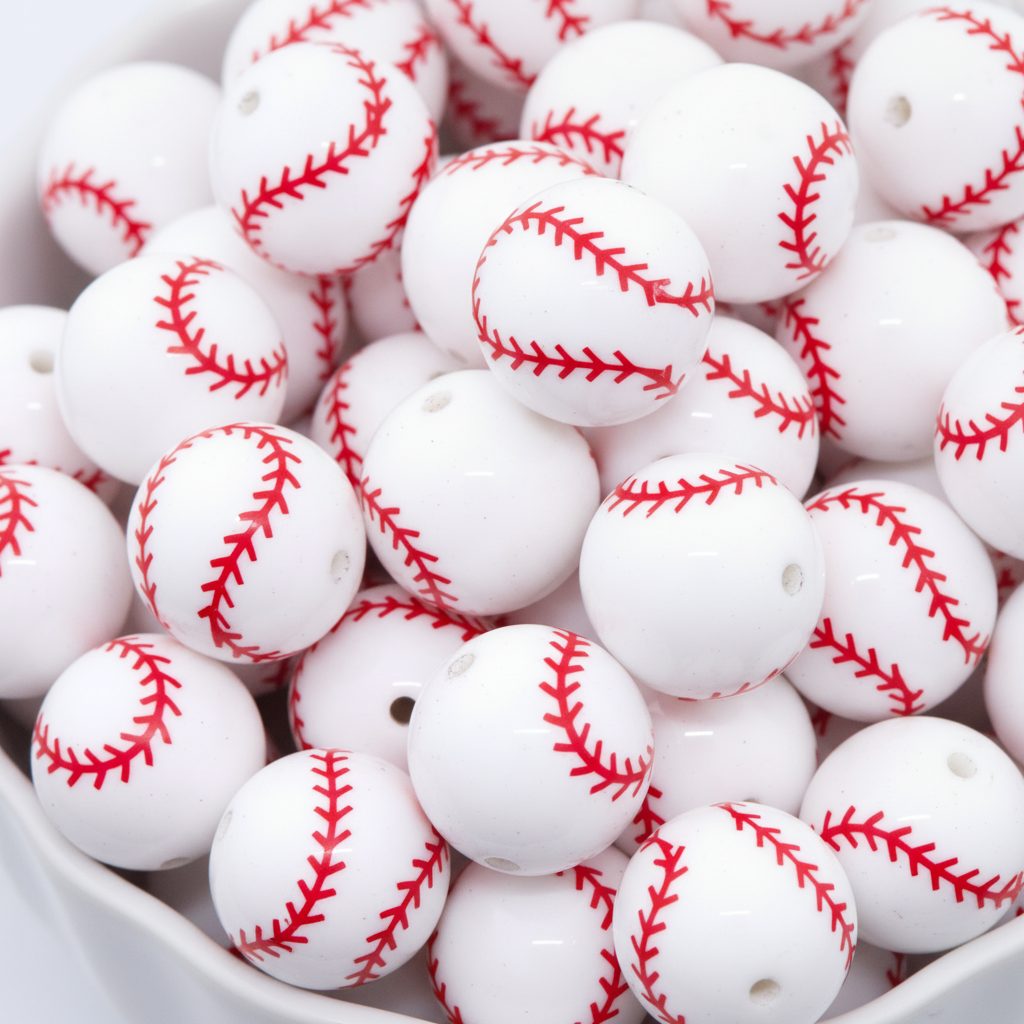 White baseball beads with red stitching pattern in a white bowl.