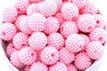 Pink beads in a white bowl on a white background 