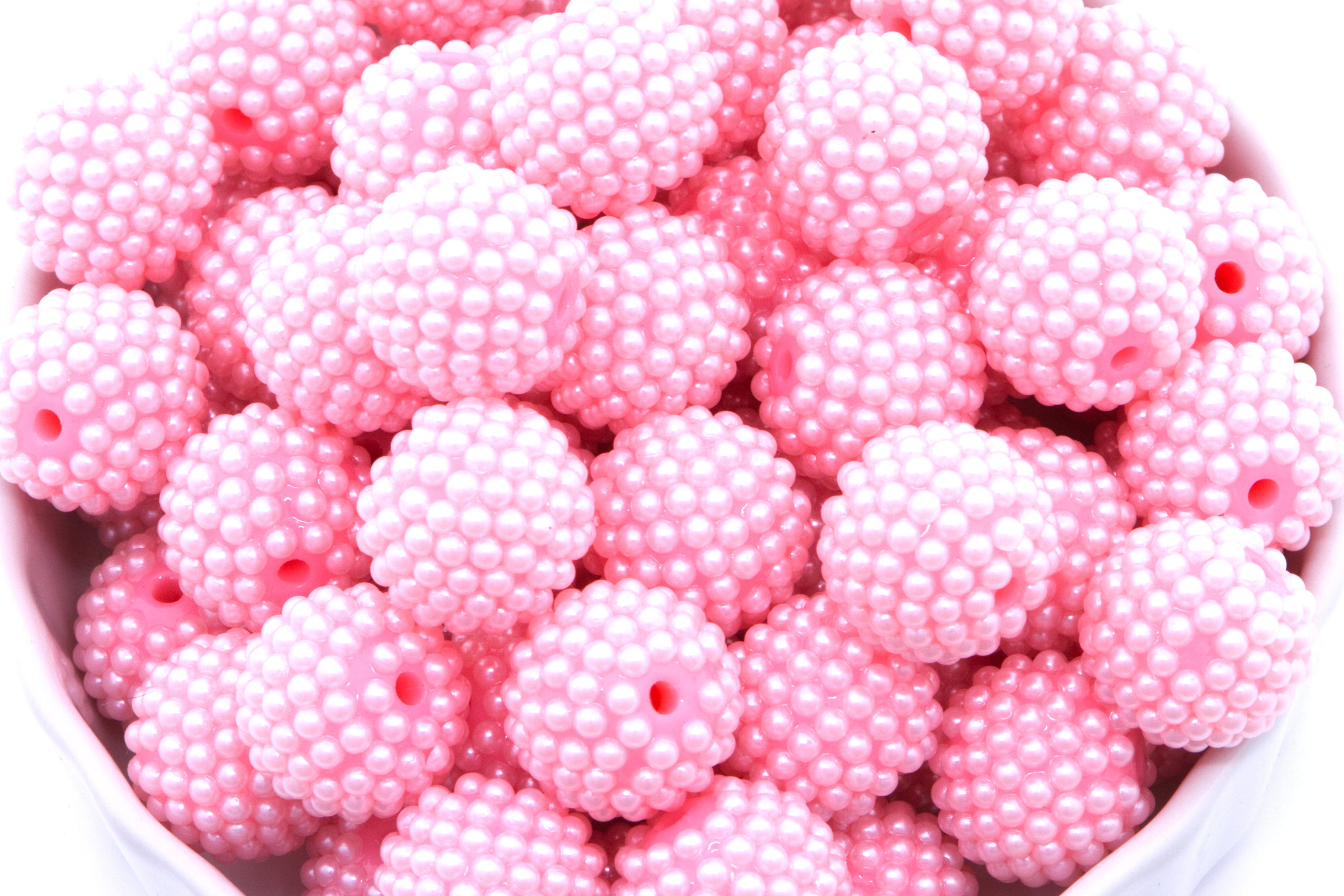 Pink beads in a white bowl on a white background 