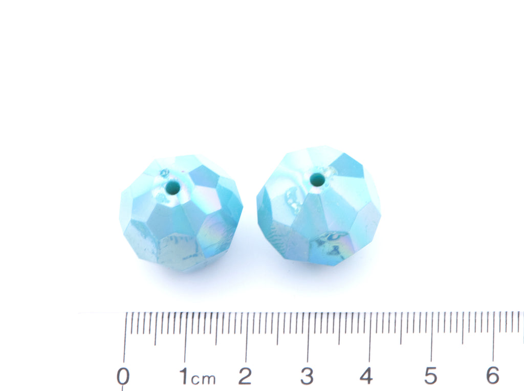 Two faceted blue beads with a ruler for scale on a white background
