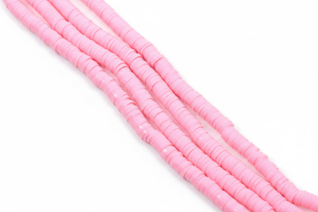 pink polymer clay disc beads arranged in diagonal strands on a plain white background.