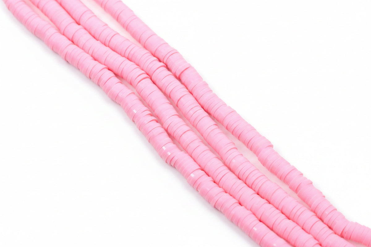 pink polymer clay disc beads arranged in diagonal strands on a plain white background.